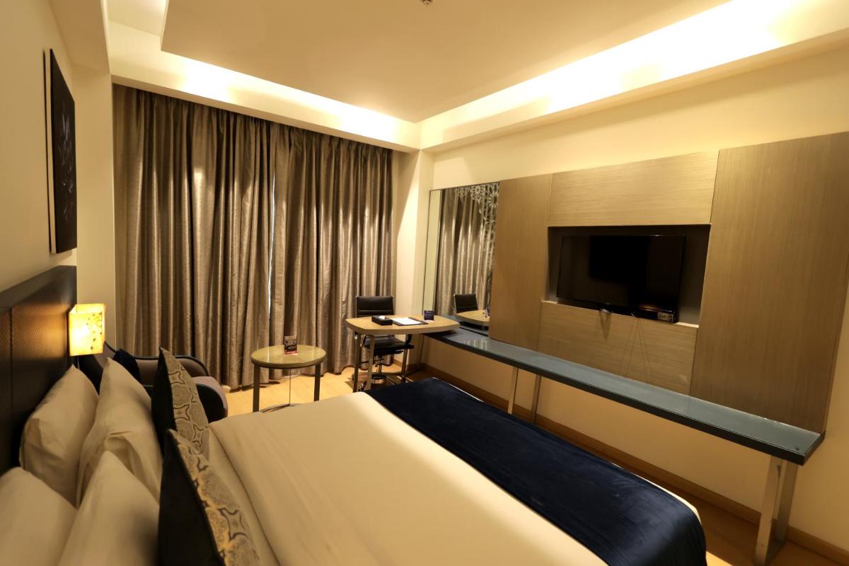 a hotel room with a bed and a flat screen tv at Ramada by Wyndham Lucknow Hotel and Convention Center in Lucknow