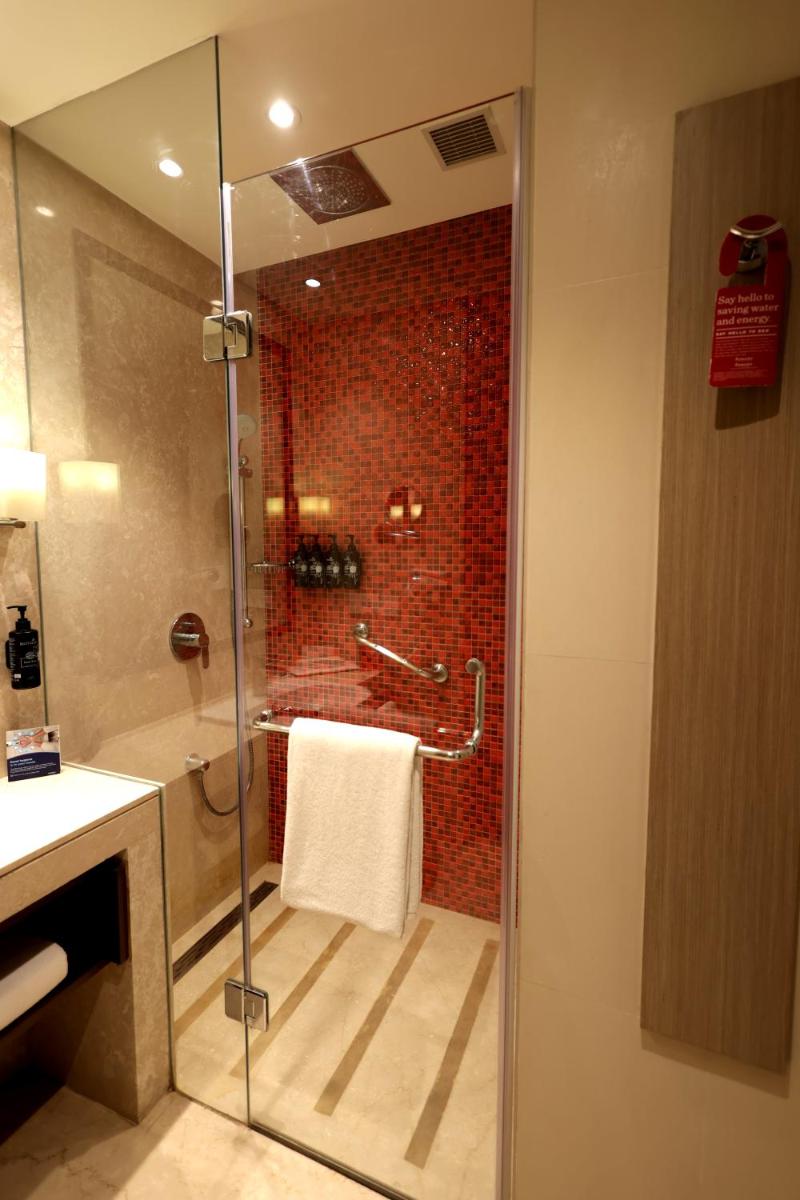 a bathroom with a shower with a glass door at Ramada by Wyndham Lucknow Hotel and Convention Center in Lucknow