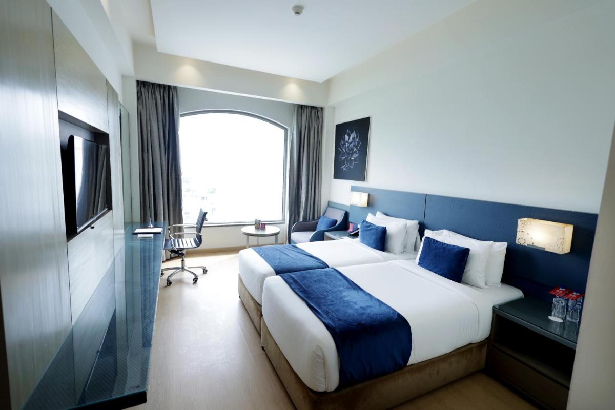 a hotel room with a large bed and a window at Ramada by Wyndham Lucknow Hotel and Convention Center in Lucknow