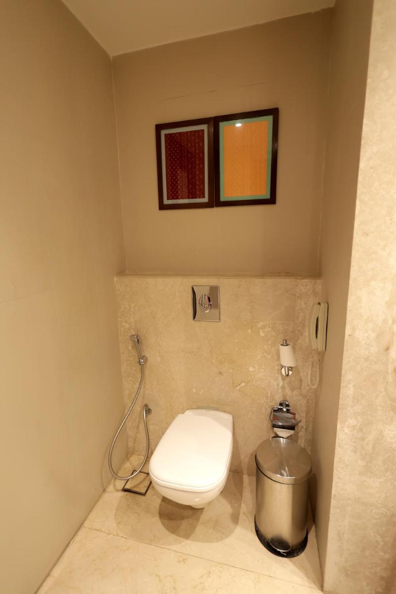 a bathroom with a toilet and a trash can at Ramada Plaza by Wyndham Lucknow in Lucknow