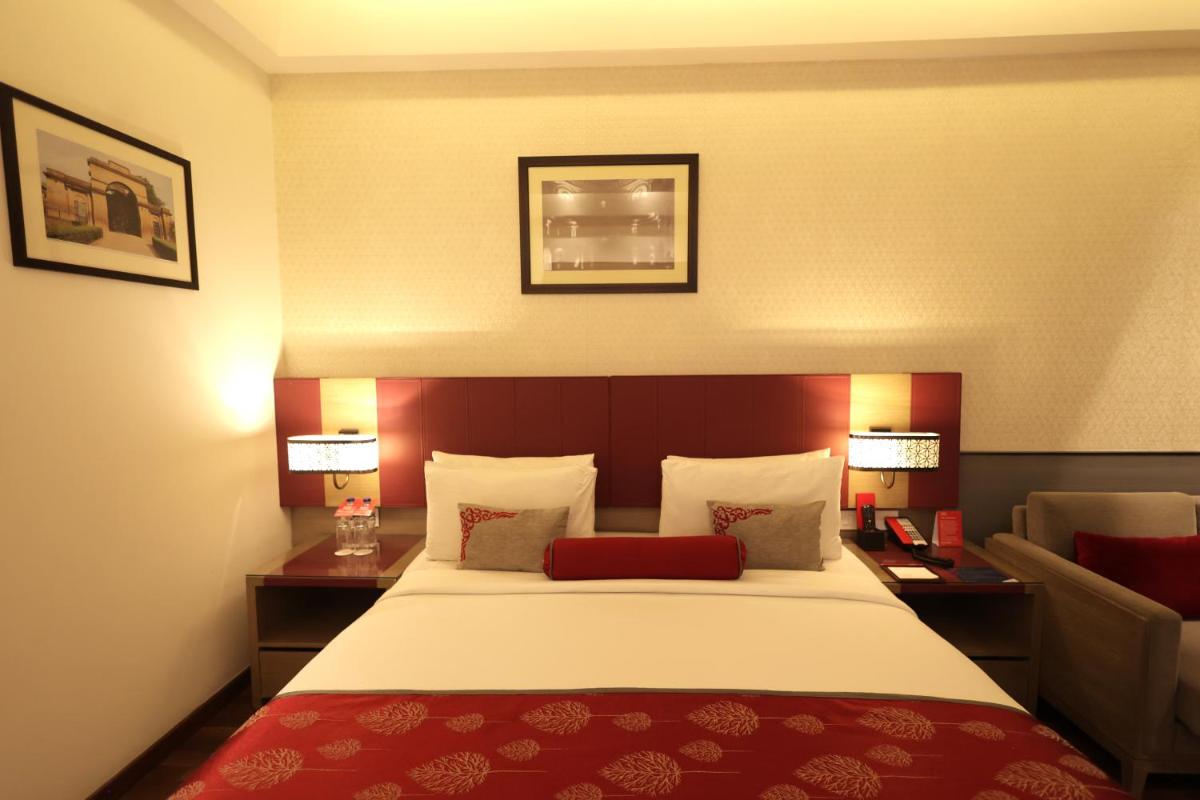 a hotel room with a large bed and two tables at Ramada Plaza by Wyndham Lucknow in Lucknow