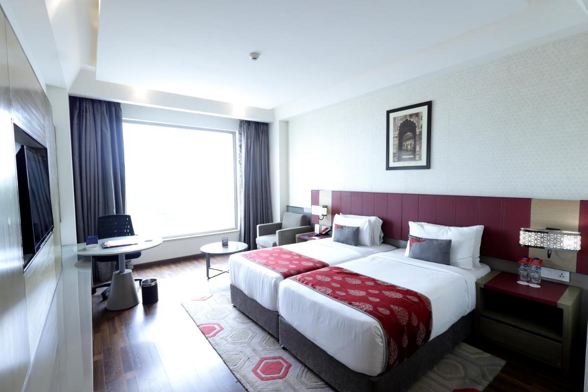 a hotel room with a large bed and a large window at Ramada Plaza by Wyndham Lucknow in Lucknow
