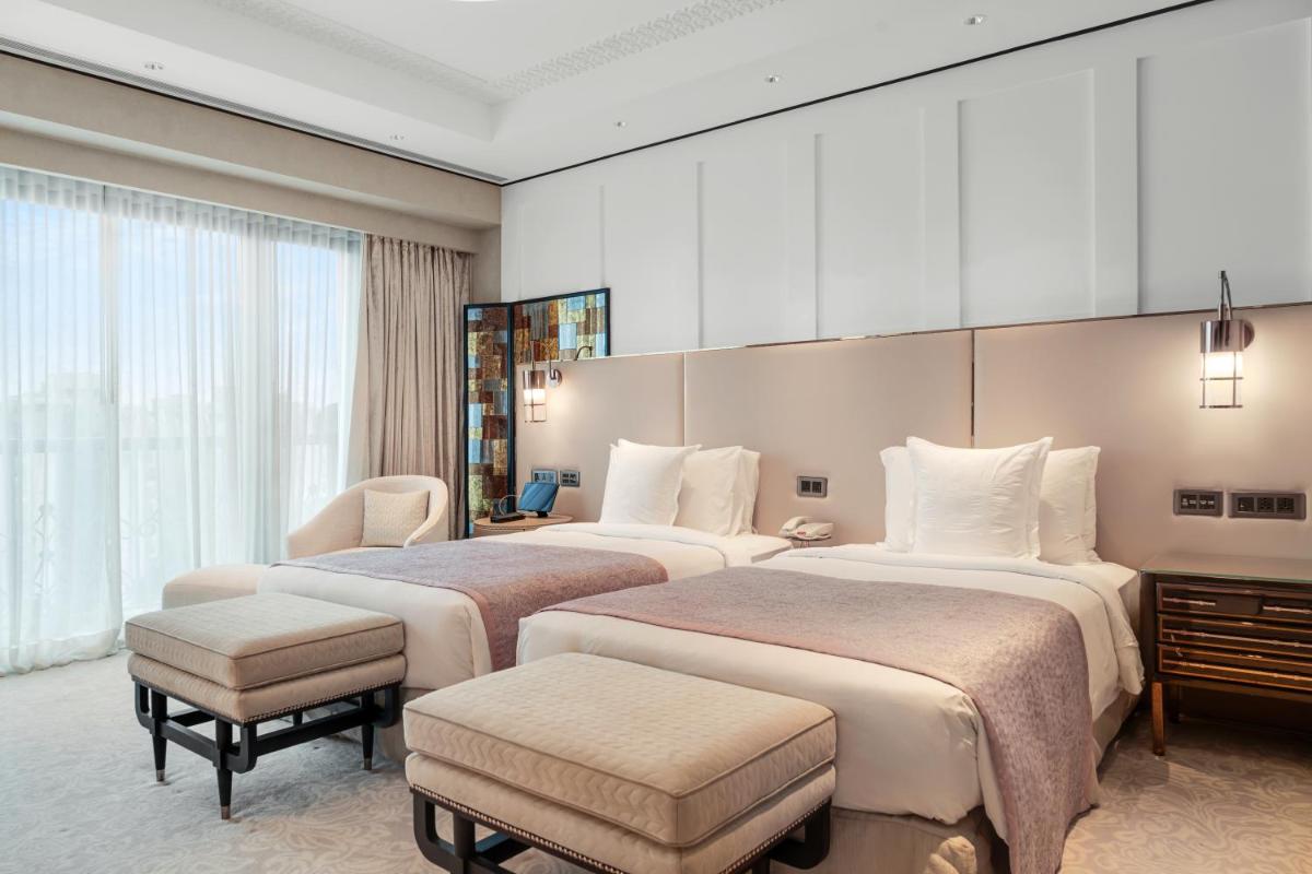 a hotel room with two beds and a chair at ITC Narmada, a Luxury Collection Hotel, Ahmedabad in Ahmedabad
