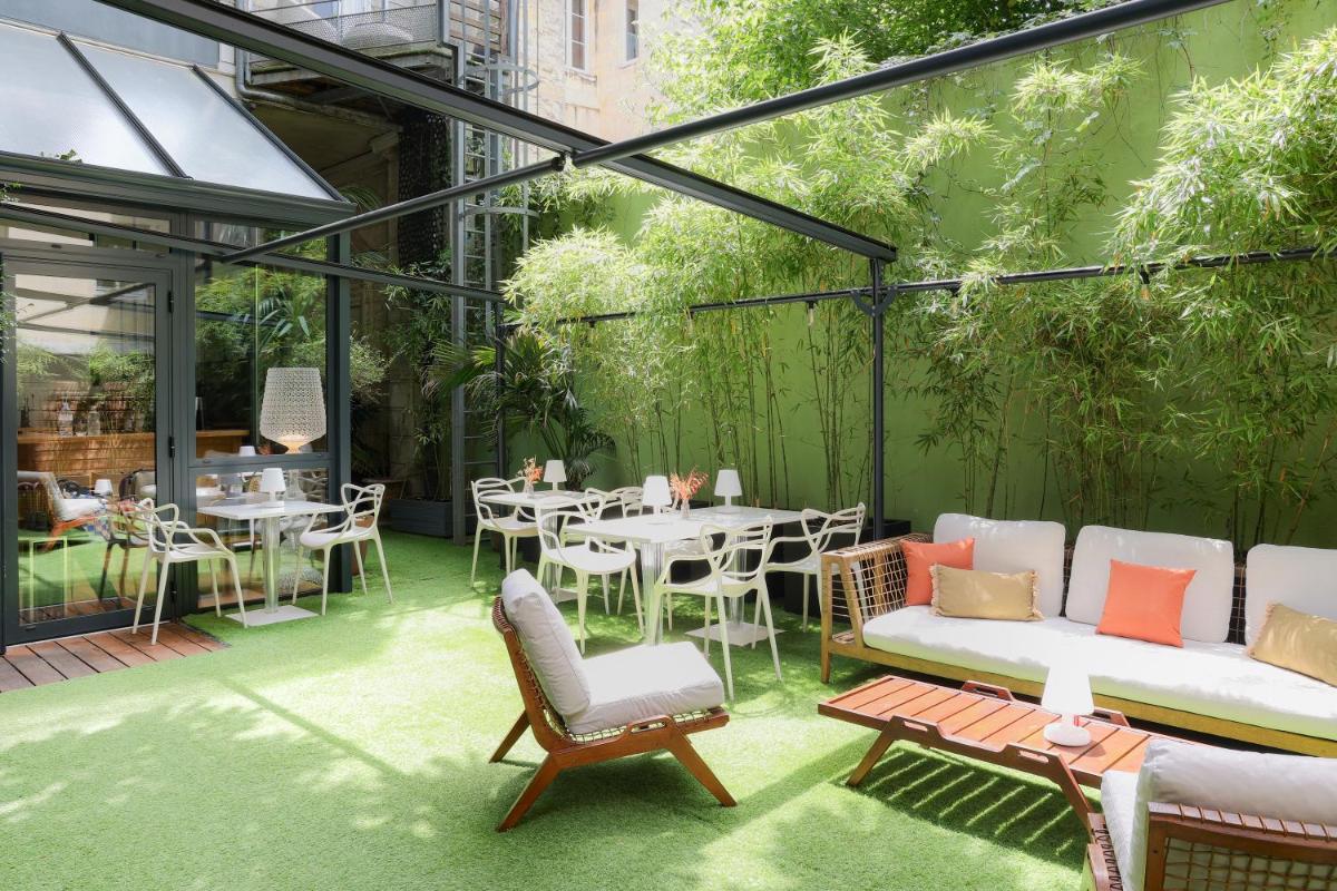 un patio avec tables et chaises dans un bâtiment dans l'établissement Le Boutique Hotel & Spa, à Bordeaux