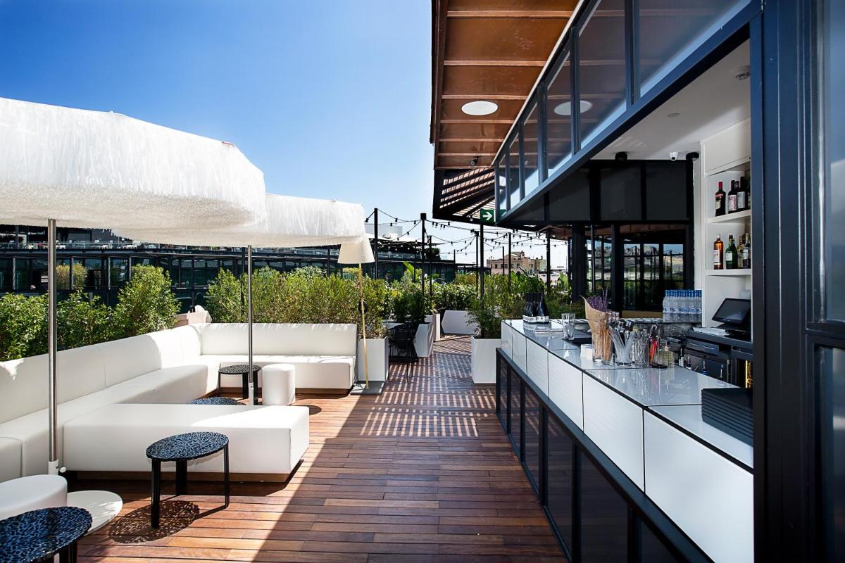 Un patio al aire libre con sofás blancos y un bar. en Monument Hotel, en Barcelona