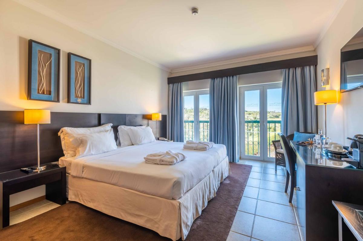 um quarto de hotel com uma cama grande e uma escrivaninha em Vale d'Oliveiras Quinta Resort & Spa em Carvoeiro