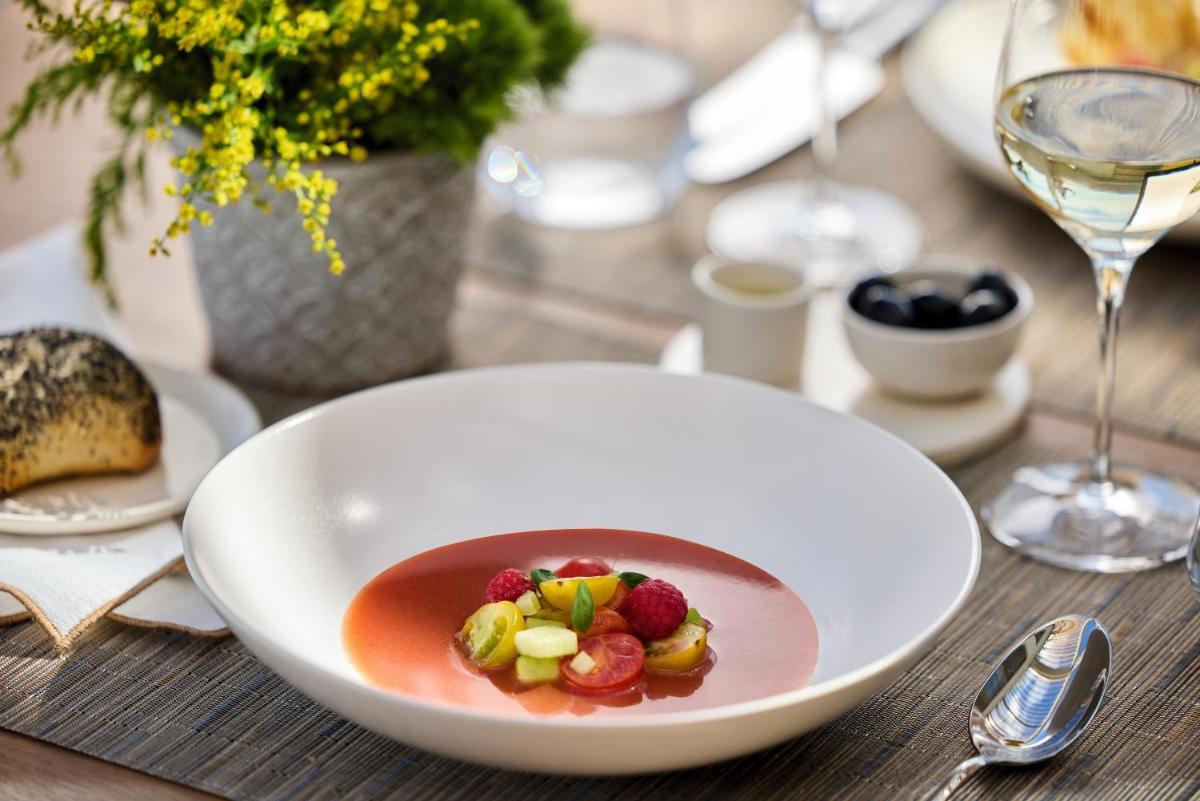 Un tazón de sopa con fruta en una mesa. en Ikos Andalusia, en Estepona