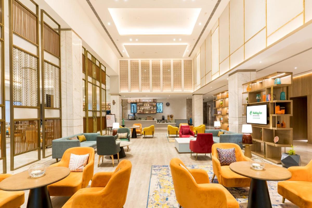 a library with couches and tables and chairs at Holiday Inn Lucknow Airport by IHG in Lucknow
