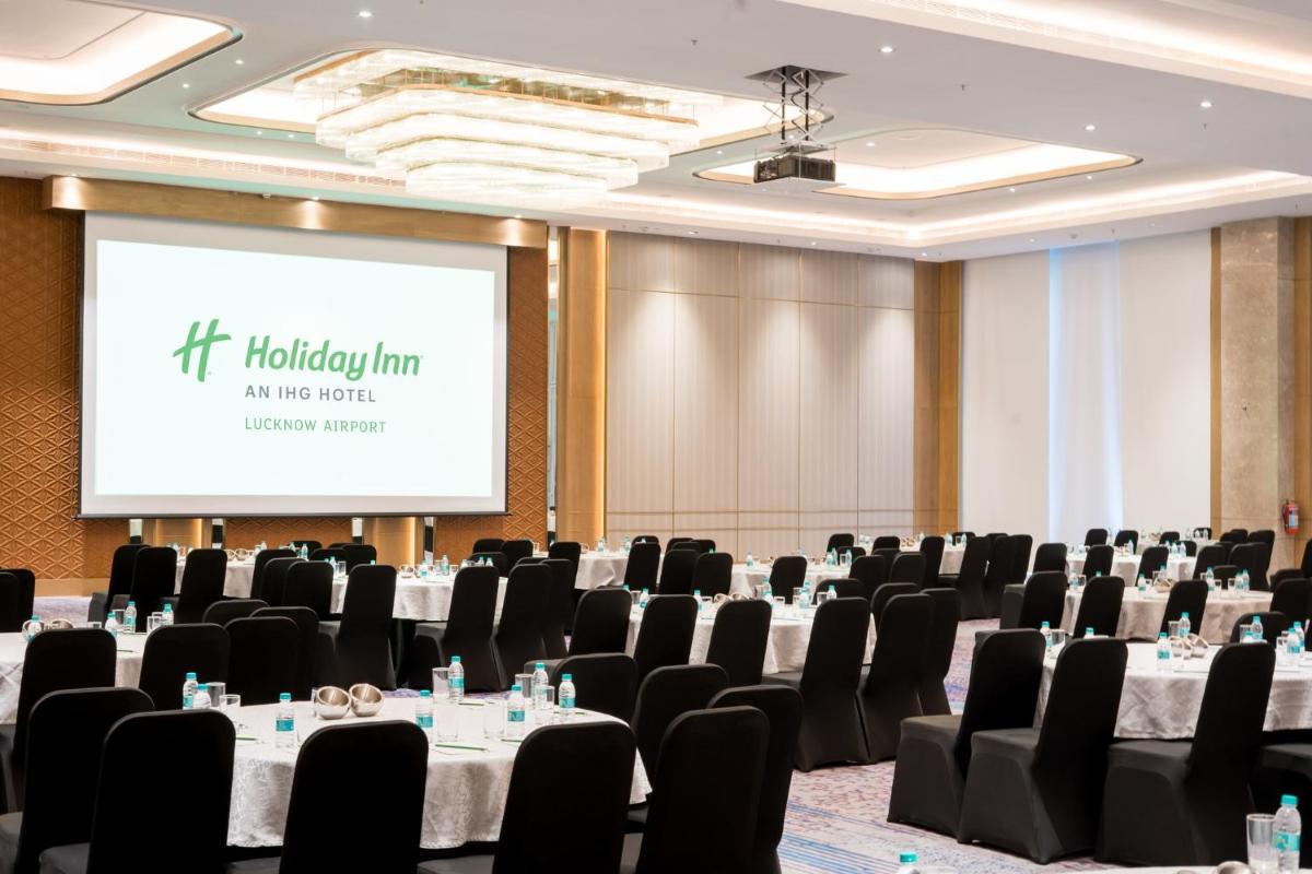 a conference room with tables and chairs and a screen at Holiday Inn Lucknow Airport by IHG in Lucknow
