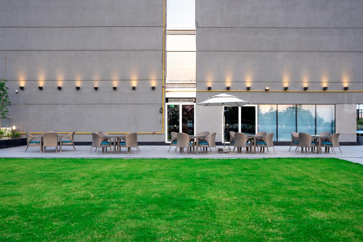 a patio with tables and chairs next to a building at Holiday Inn Lucknow Airport by IHG in Lucknow