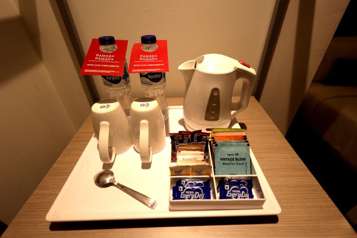 a table with a tea kettle and a tray of food at Ramada by Wyndham Lucknow Hotel and Convention Center in Lucknow