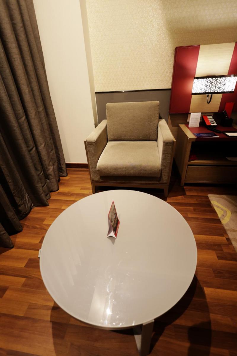 a living room with a white table and a chair at Ramada by Wyndham Lucknow Hotel and Convention Center in Lucknow
