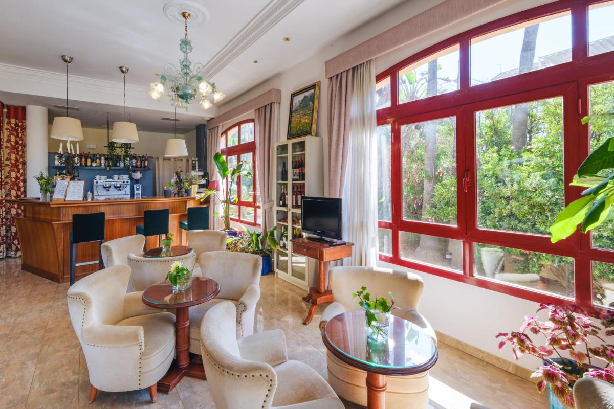 una sala de estar con sillas blancas y un bar en Hotel Ciutat Jardi, en Palma de Mallorca
