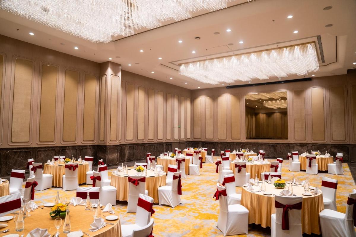 a banquet hall with tables and chairs and a chandelier at Novotel Kolkata Hotel and Residences in Kolkata a banquet hall with tables and chairs and a chandelier at Novotel Kolkata Hotel and Residences in Kolkata