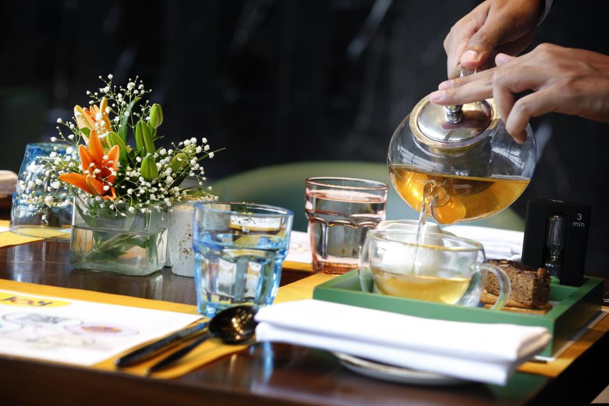 a person pouring tea from a tea kettle on a table at Novotel Kolkata Hotel and Residences in Kolkata a person pouring tea from a tea kettle on a table at Novotel Kolkata Hotel and Residences in Kolkata