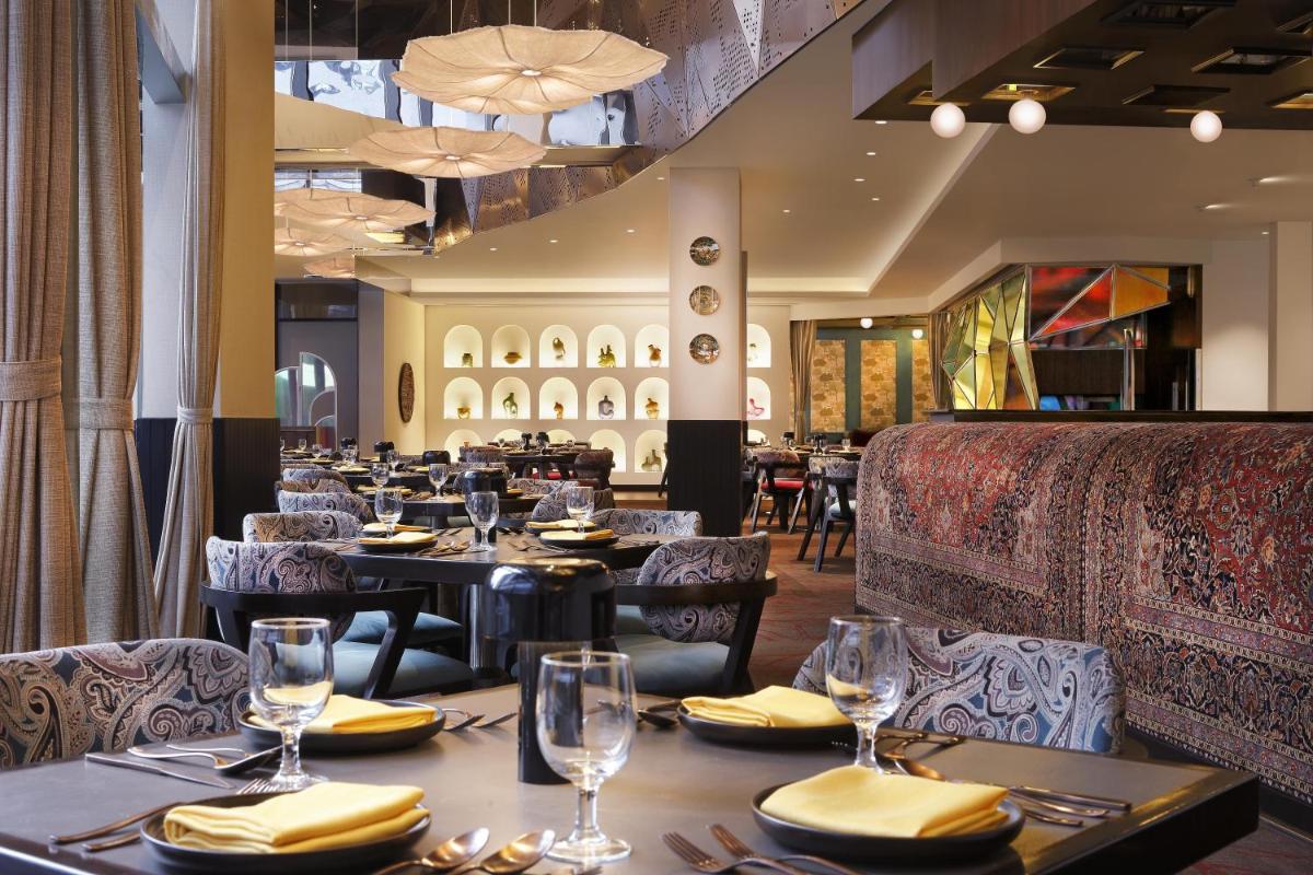 a dining room with tables and chairs in a restaurant at Novotel Kolkata Hotel and Residences in Kolkata a dining room with tables and chairs in a restaurant at Novotel Kolkata Hotel and Residences in Kolkata