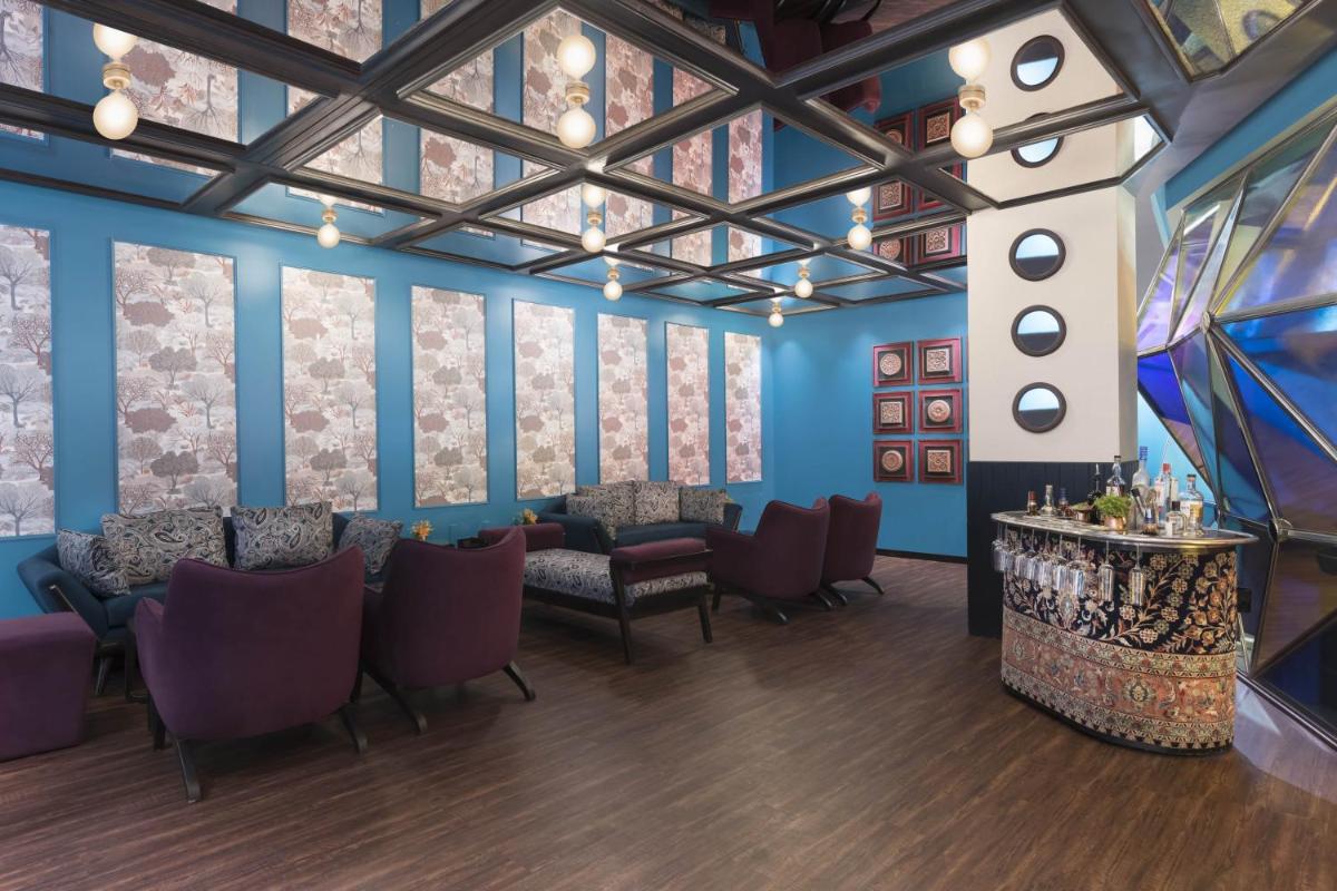 a room with blue walls and chairs and a bar at Novotel Kolkata Hotel and Residences in Kolkata a room with blue walls and chairs and a bar at Novotel Kolkata Hotel and Residences in Kolkata