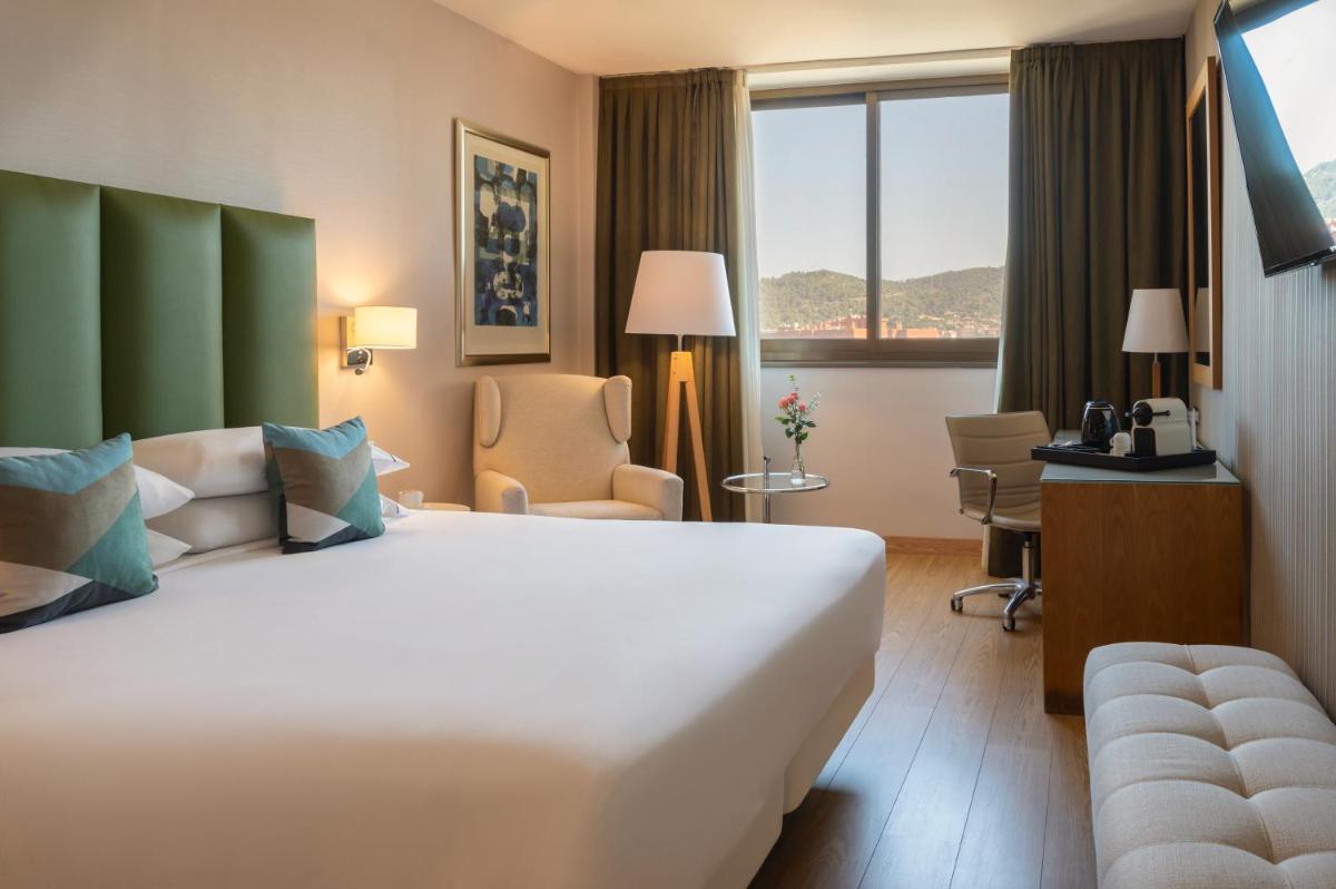 Una habitación de hotel con una gran cama blanca y una ventana. en Hesperia Barcelona Sant Just, en Sant Just Desvern