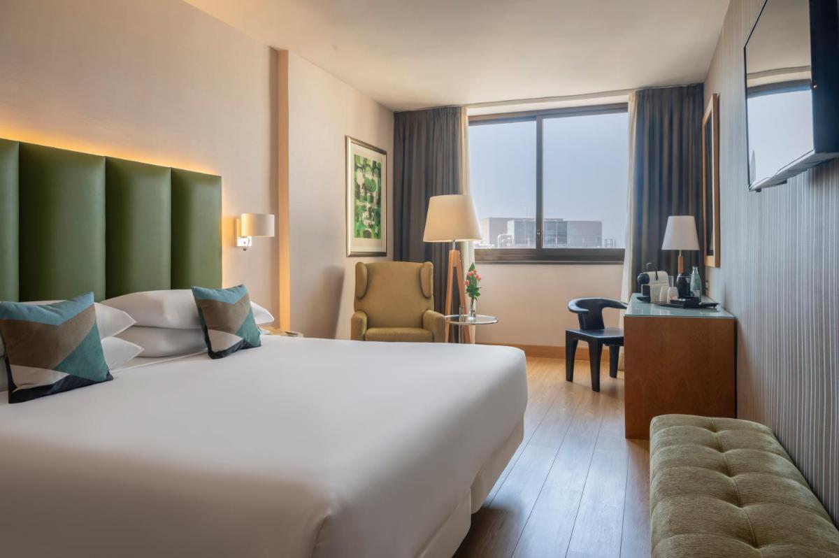 Una habitación de hotel con una gran cama blanca y una ventana. en Hesperia Barcelona Sant Just, en Sant Just Desvern