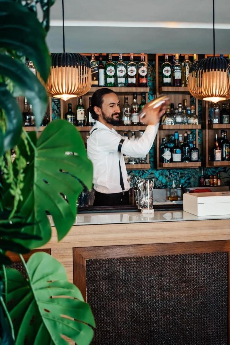 Un homme se tient derrière un bar dans l'établissement Five Seas Cannes, a Member of Design Hotels™, à Cannes