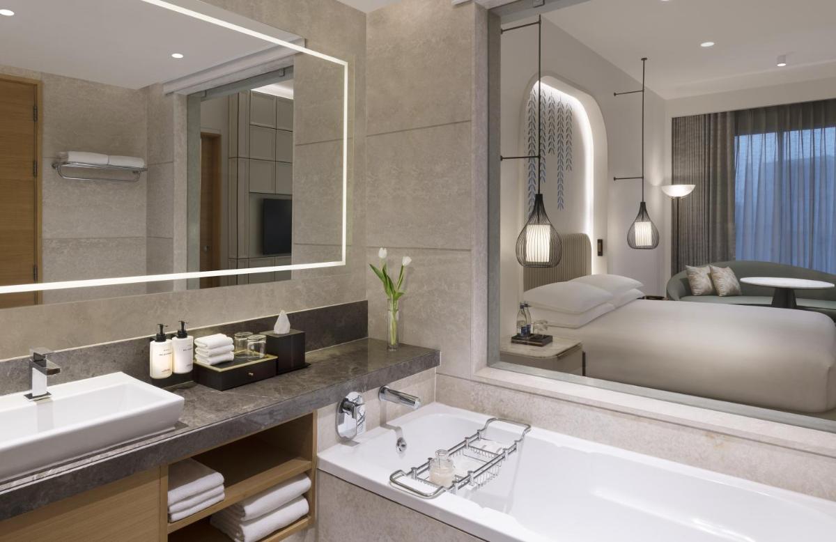 a bathroom with a large mirror and a tub and a sink at InterContinental Jaipur Tonk Road by IHG in Jaipur