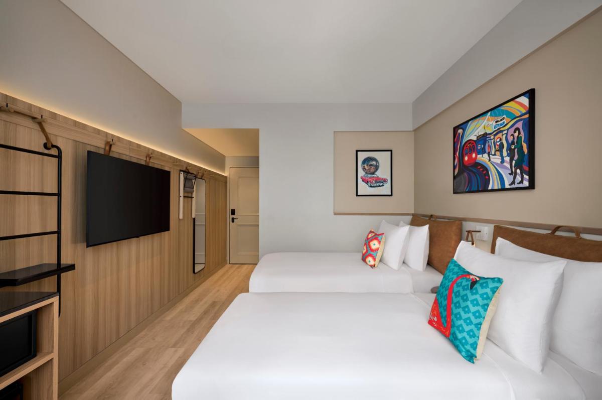 two beds in a hotel room with a flat screen tv at Moxy Mumbai Andheri West in Mumbai