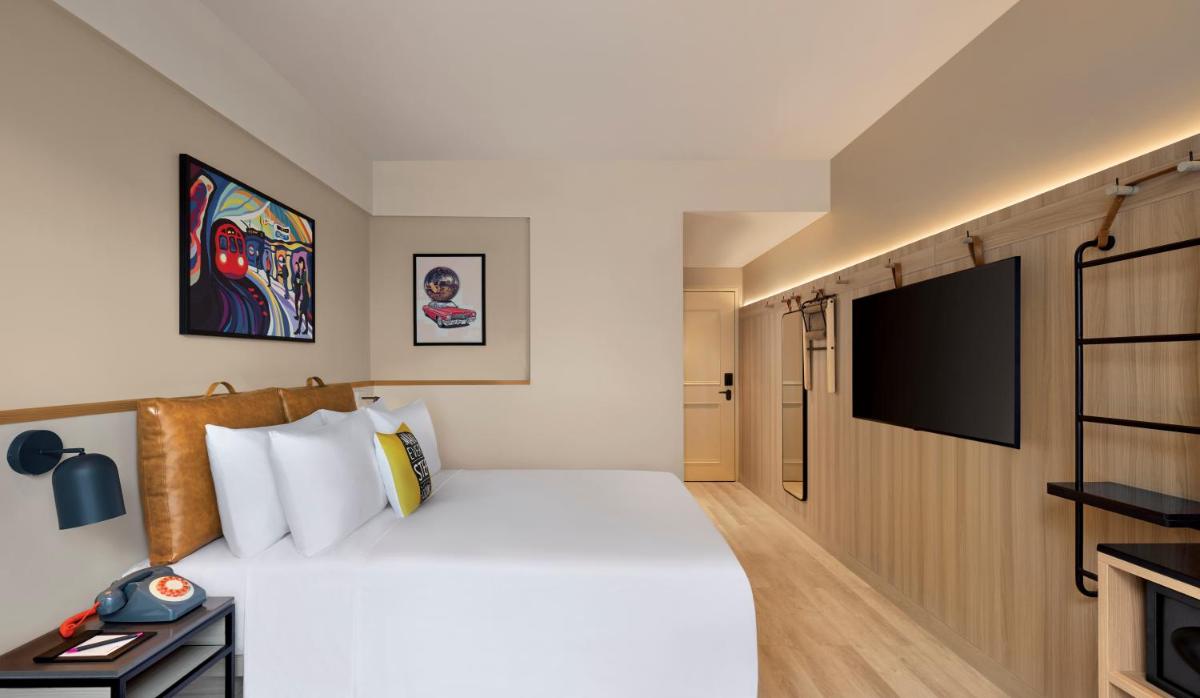 a hotel room with a bed and a flat screen tv at Moxy Mumbai Andheri West in Mumbai