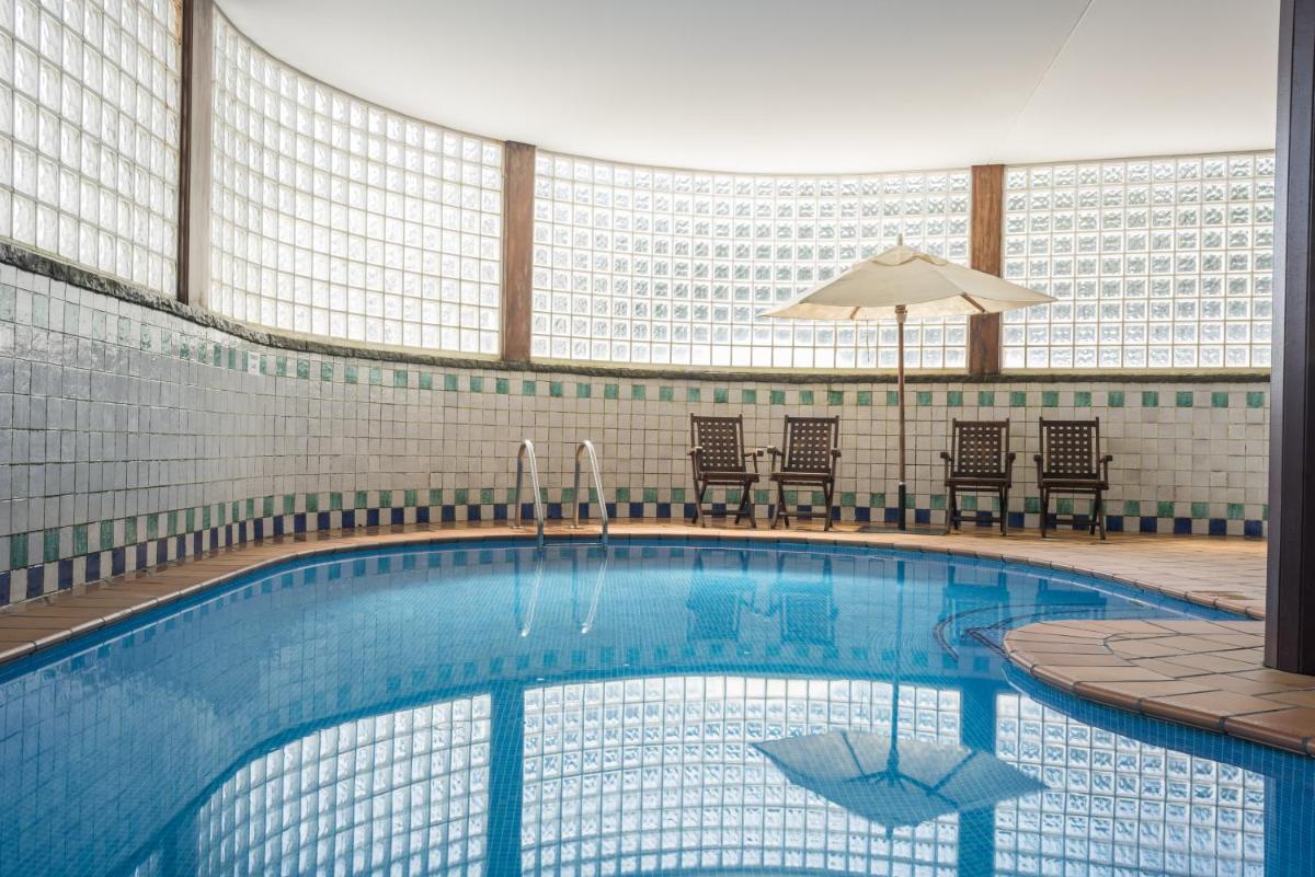 una gran piscina con sillas y sombrilla en Snö Hotel Formigal, en Formigal