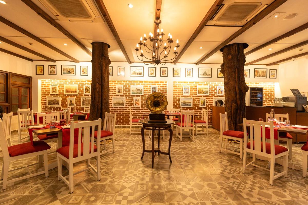 a restaurant with tables and chairs and a chandelier at Saraca Hotel Lucknow in Lucknow