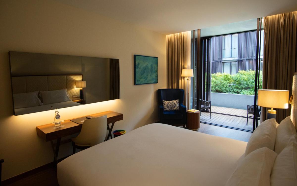 um quarto de hotel com uma cama e uma secretária e um quarto em Boeira Garden Hotel Porto Gaia, Curio Collection by Hilton em Vila Nova de Gaia