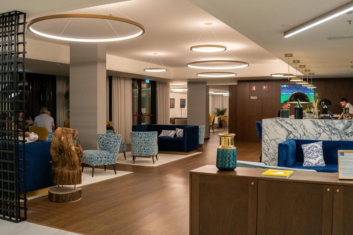 um lobby com mobiliário azul e pessoas ao fundo em Boeira Garden Hotel Porto Gaia, Curio Collection by Hilton em Vila Nova de Gaia