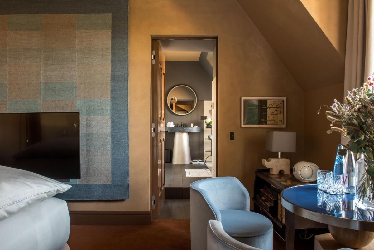 une chambre avec un lit, une table et un miroir dans l'établissement Cour des Vosges - Evok Collection, à Paris