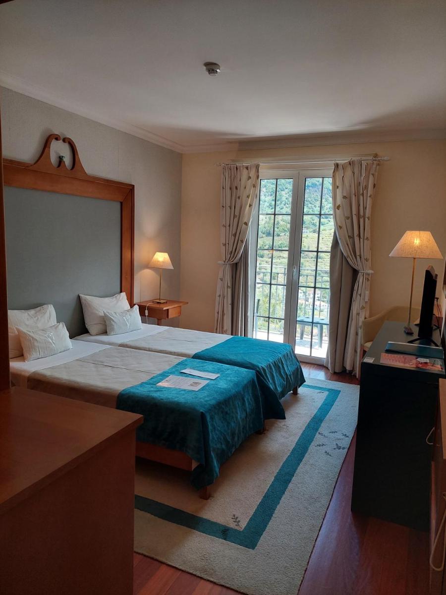 um quarto com uma cama grande e uma janela grande em Estalagem do Vale em São Vicente