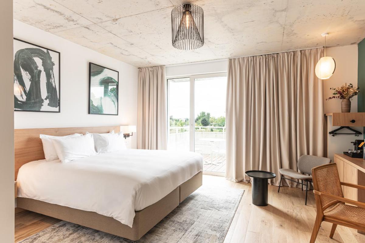 une chambre avec un grand lit et une grande fenêtre dans l'établissement voco Beaune , Cité des Vins by IHG, à Beaune
