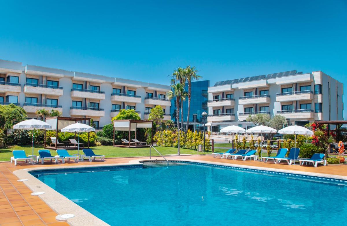 Una piscina frente a un hotel con sillas y sombrillas. en Hotel Spa Galatea, en Sanxenxo