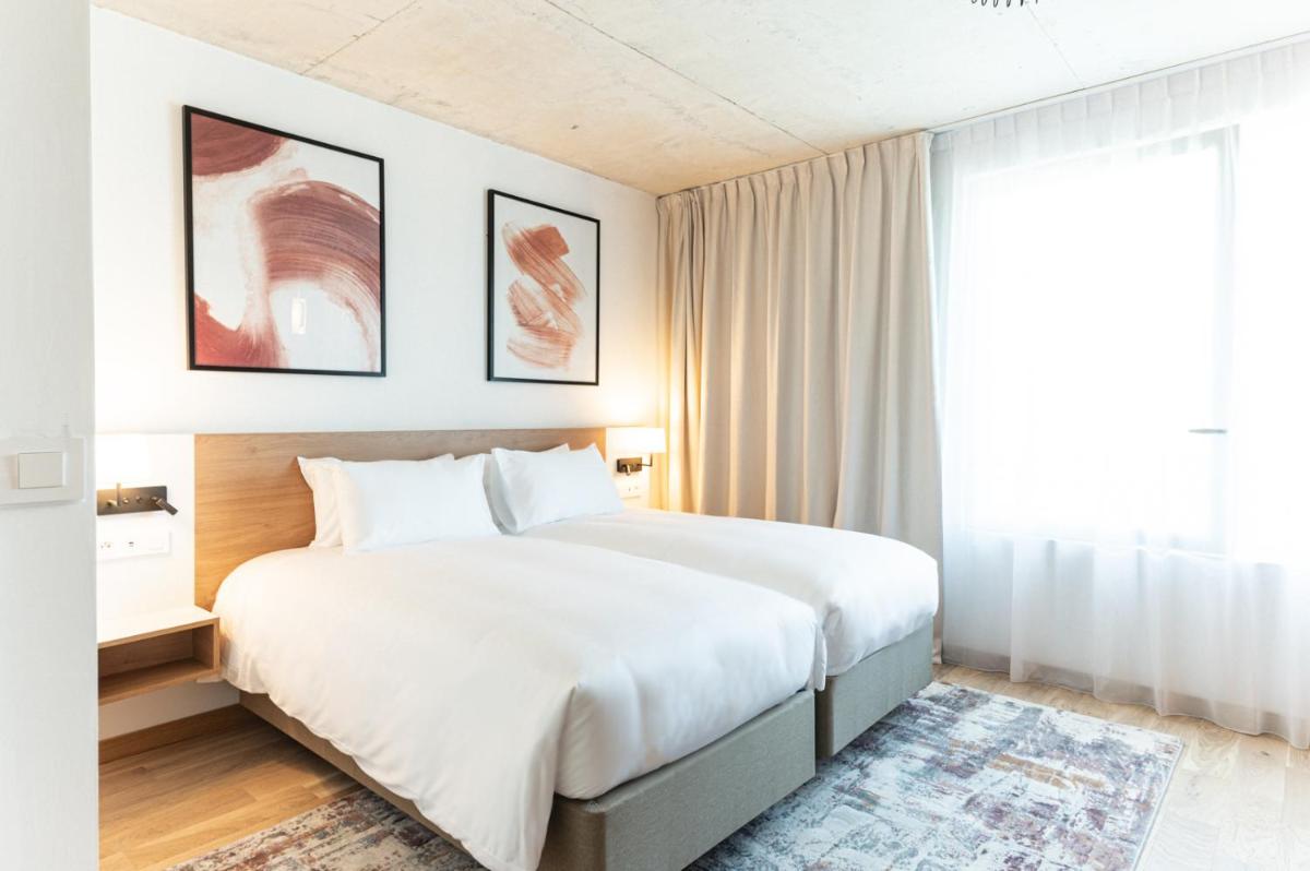 une chambre avec un grand lit blanc et une fenêtre dans l'établissement voco Beaune , Cité des Vins by IHG, à Beaune