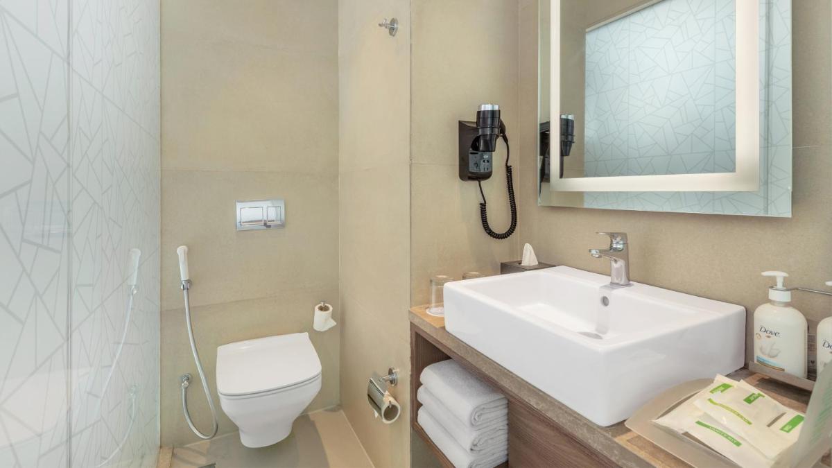 a bathroom with a sink and a toilet and a phone at Holiday Inn Gurugram Sector 90 by IHG in Gurgaon