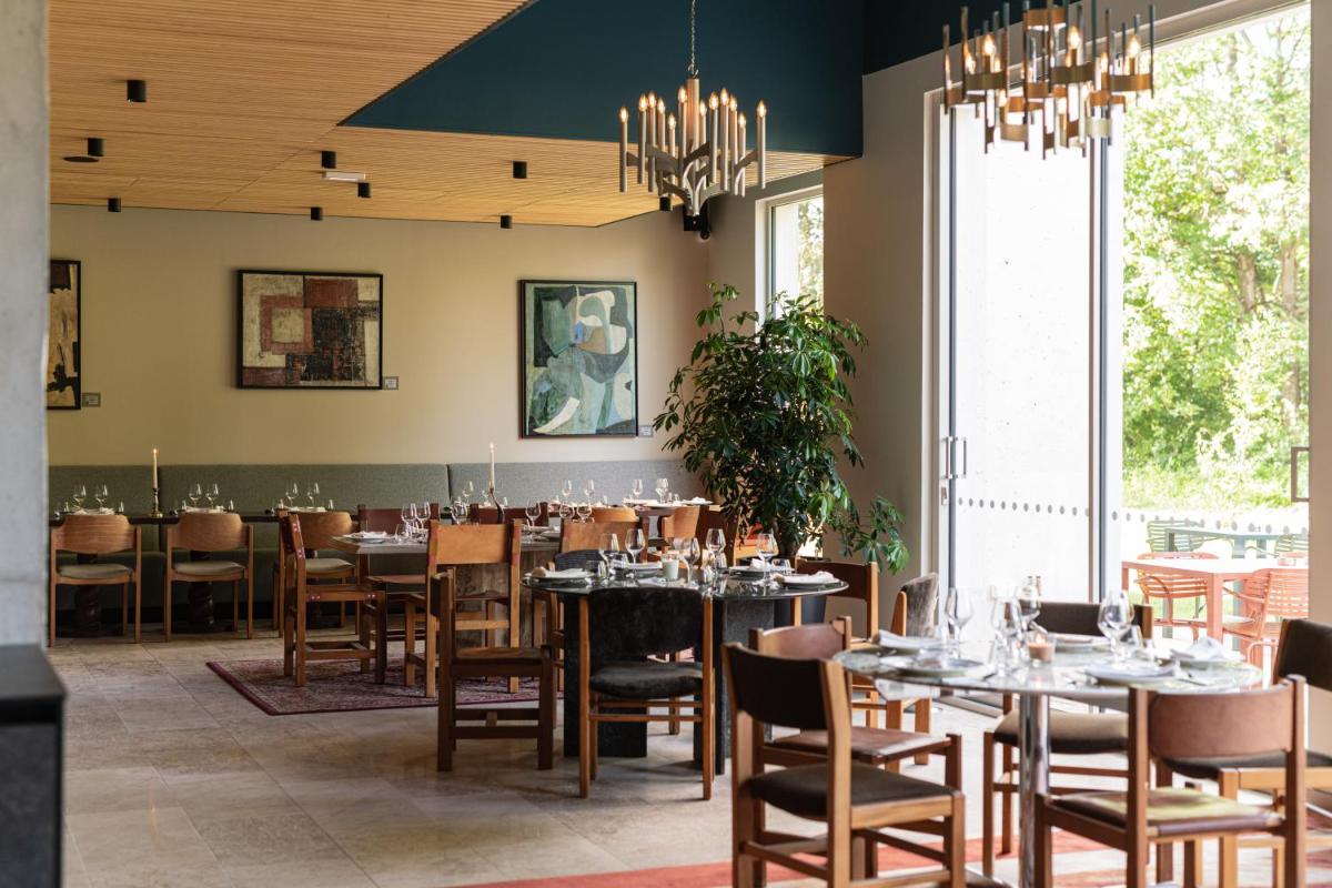 une salle à manger avec tables, chaises et un lustre dans l'établissement voco Beaune , Cité des Vins by IHG, à Beaune