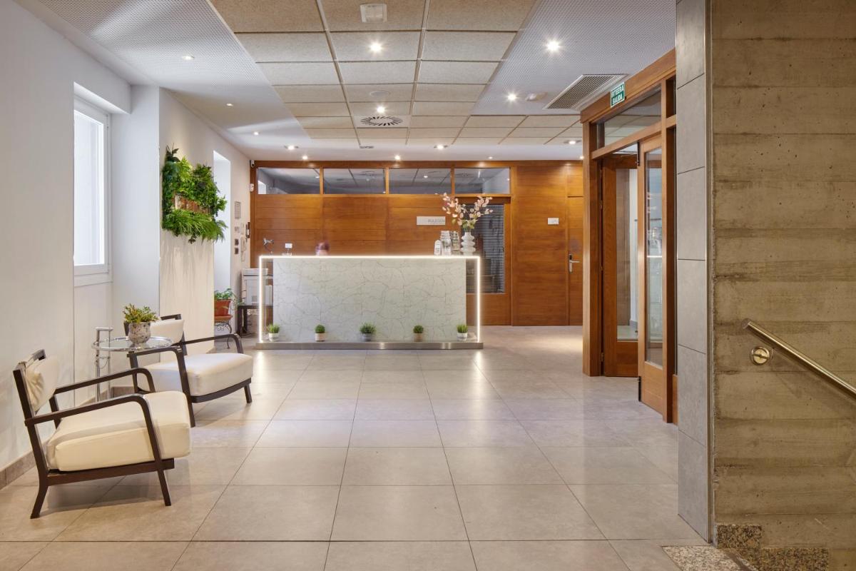 Un pasillo de oficina con sillas y un mostrador de recepción. en Iraipe Santuario de Arantzazu Hotel, en Oñate