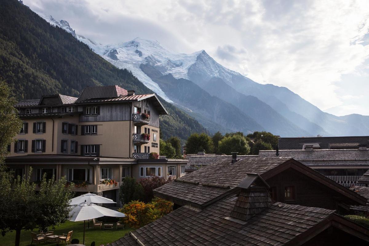 une vue d'un bâtiment avec des montagnes en arrière-plan dans l'établissement Le Hameau Albert 1er - Relais & Châteaux, à Chamonix-Mont-Blanc