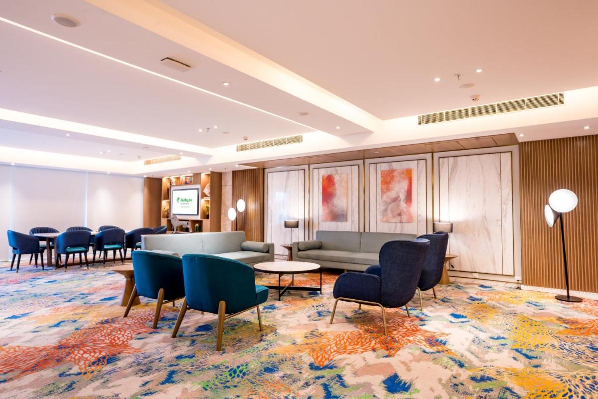a waiting room with chairs and a couch and tables at Holiday Inn Lucknow Airport by IHG in Lucknow