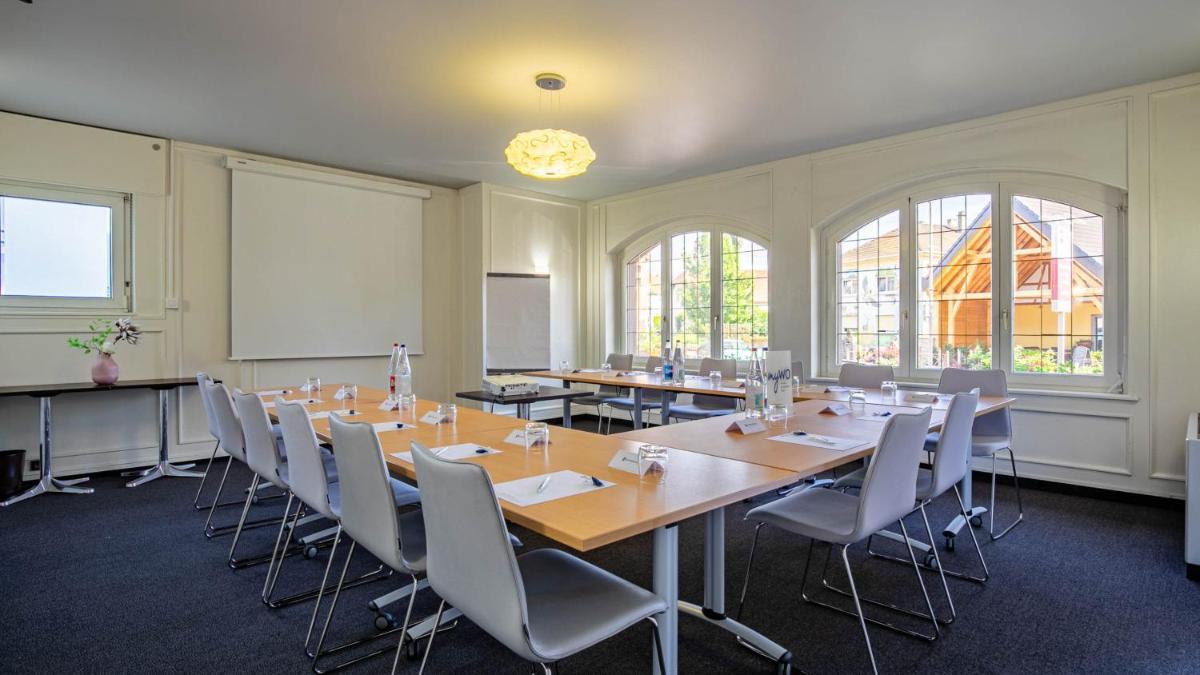 une salle de conférence avec des tables, des chaises et un tableau blanc dans l'établissement Best Western Plus Au cheval Blanc à Mulhouse, à Baldersheim 103 autres photos