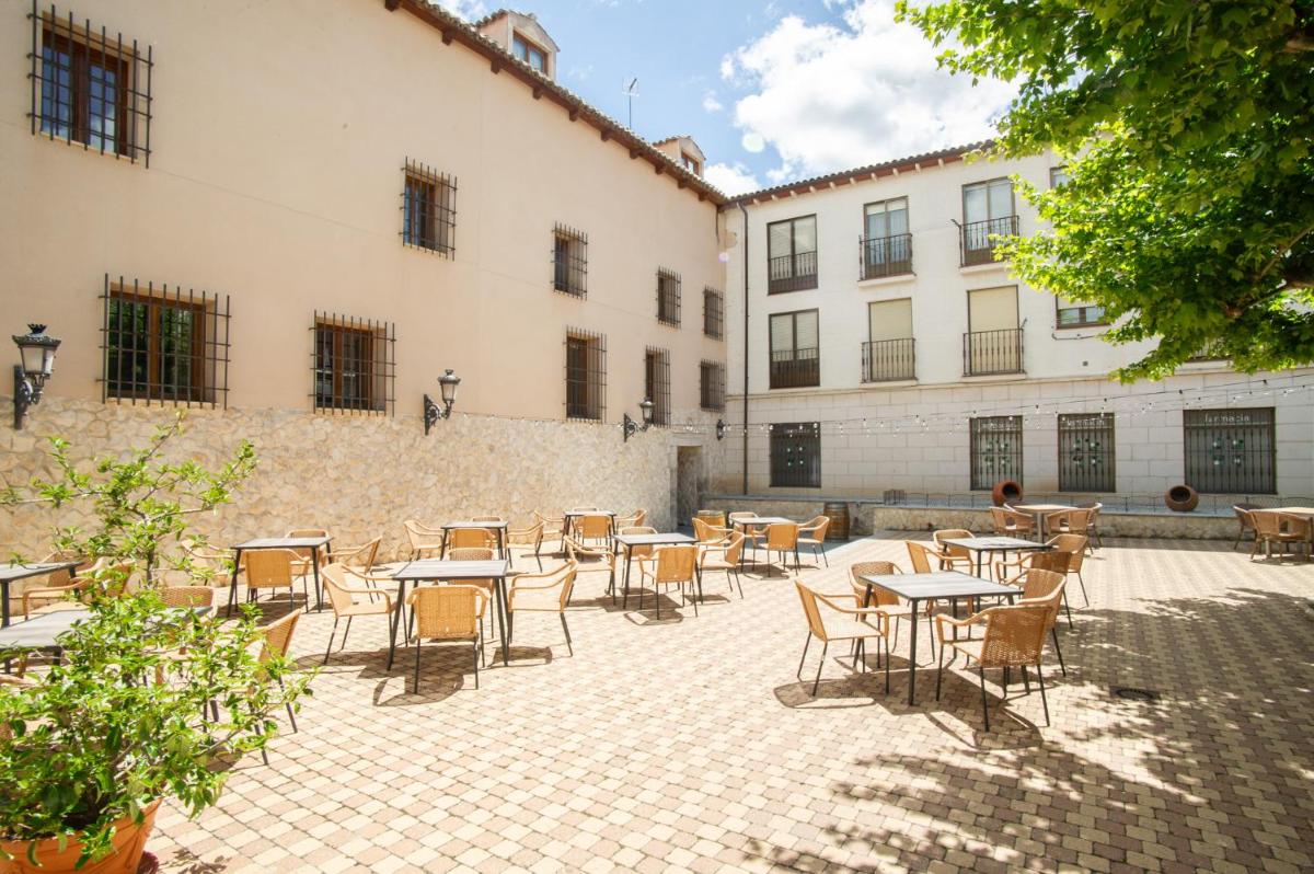 Un patio con mesas y sillas frente a un edificio. en AZZ Peñafiel Las Claras Hotel & Spa, en Peñafiel