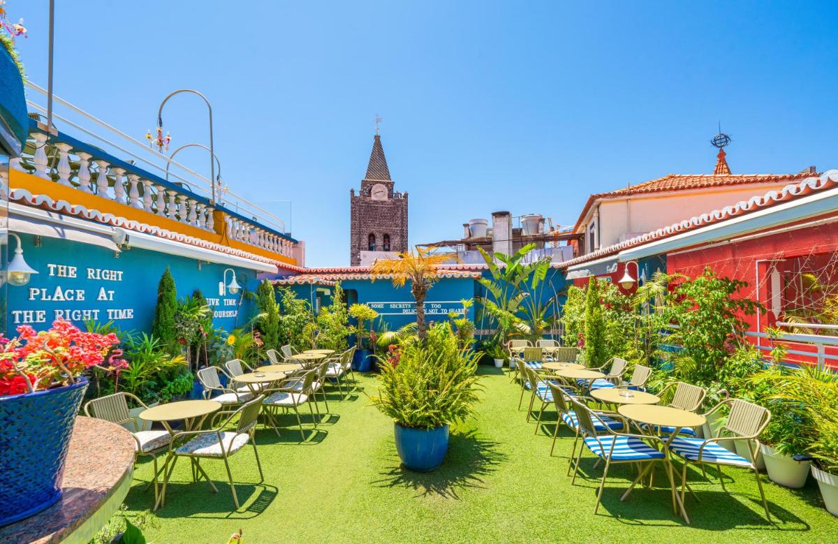 um pátio ao ar livre com mesas, cadeiras e plantas em Sé Boutique Hotel no Funchal