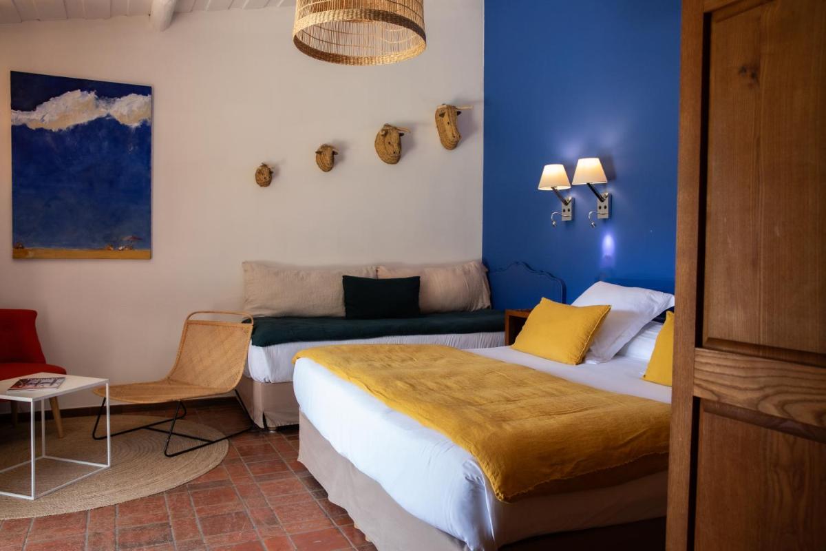une chambre d'hôtel avec deux lits et un canapé dans l'établissement Oustau Camarguen Hôtel & Spa, au Grau-du-Roi