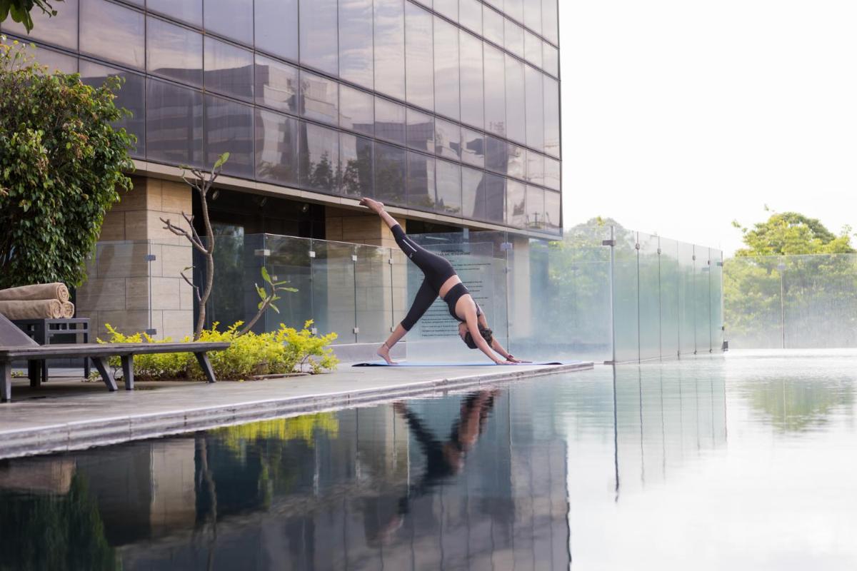 a woman doing a handstand on the edge of a swimming pool at The Den, Bengaluru in Bengaluru
