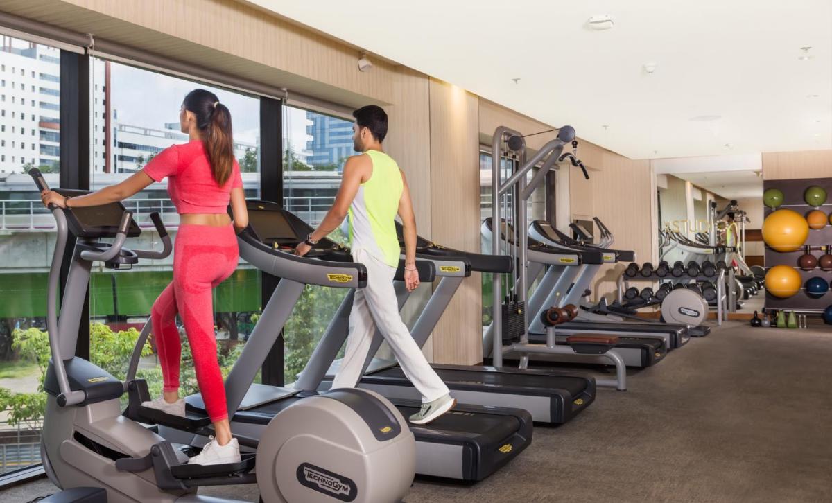 a man and a woman on a treadmill in a gym at The Den, Bengaluru in Bengaluru