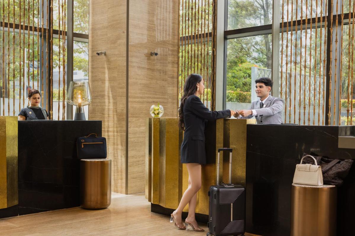 a man and a woman shaking hands in a lobby at The Den, Bengaluru in Bengaluru