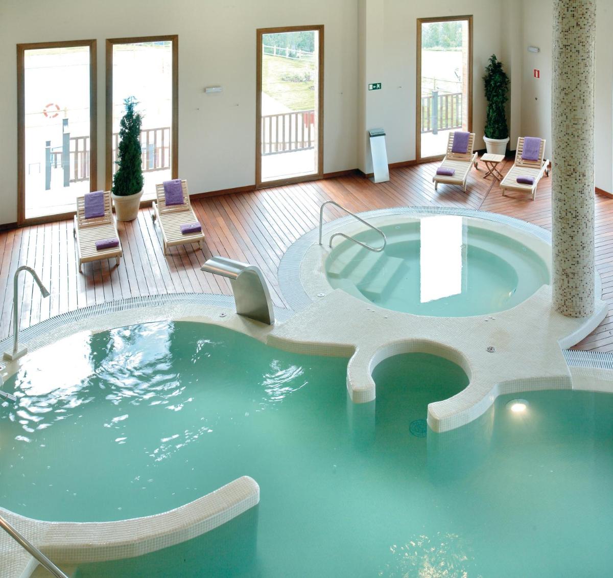 bañera de hidromasaje en medio de una habitación con sillas en Hotel & Spa Real Badaguás Jaca, en Badaguás