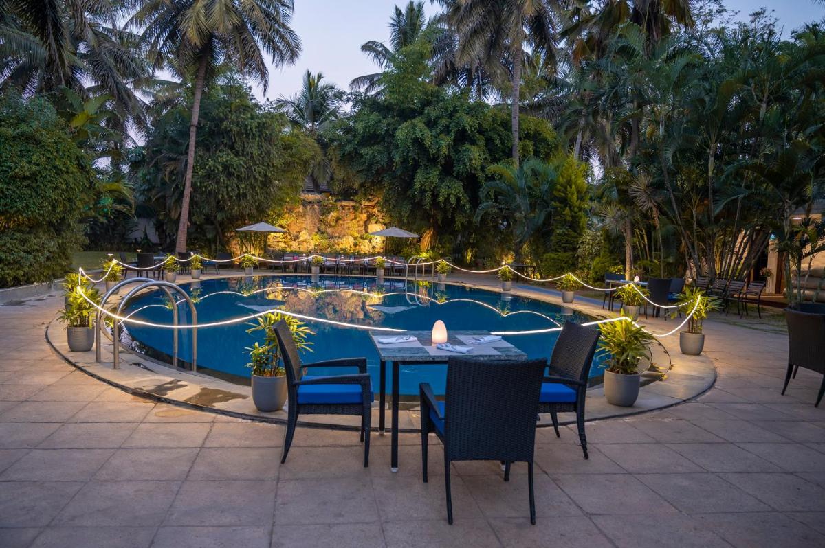 a table and chairs in front of a swimming pool at Southern Star,Mysore in Mysore